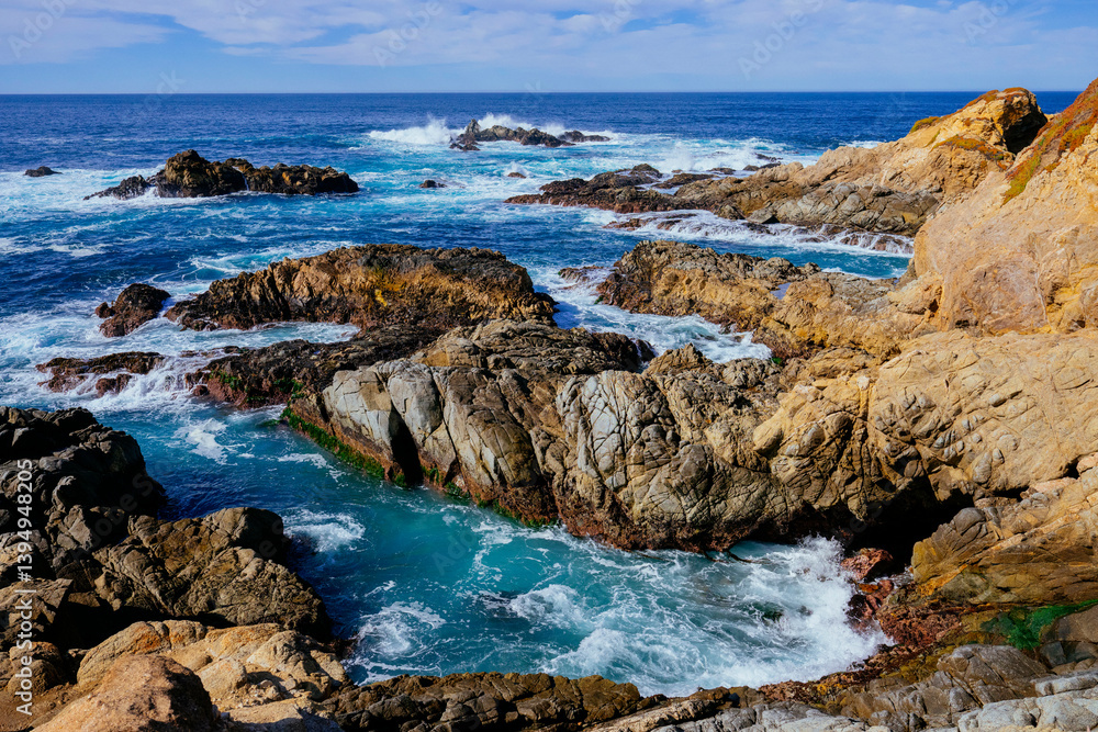 Rocky coastline with waves crashing on the shore under a bright blue sky. Monterey, CA, USA Rocky coastline with waves crashing on the shore under a bright blue sky. Monterey, CA, USA