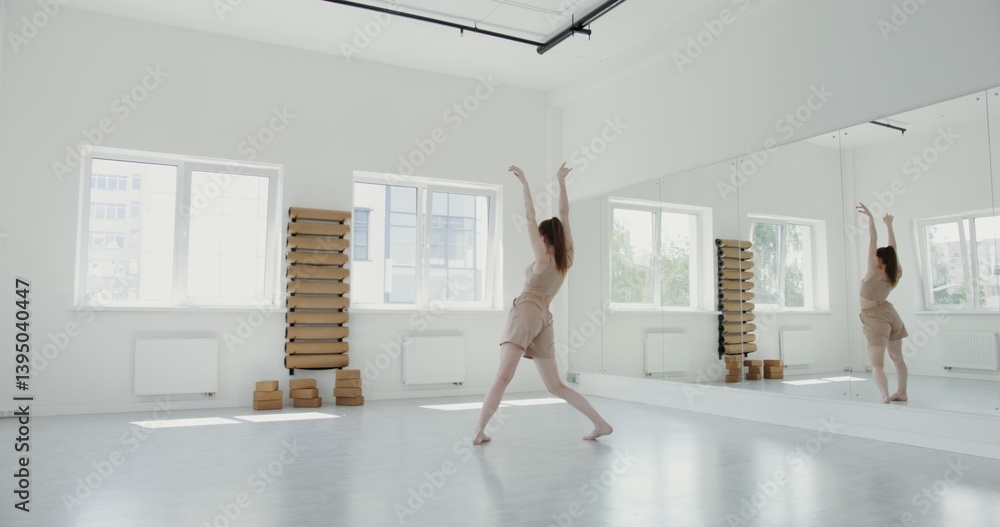 Beautiful girl of European appearance in sportswear, with collected hair, no makeup doing rhythmic ballet lunges in a modern light gym for gymnastics Beautiful girl of European appearance in sportswear, with collected hair, no makeup doing rhythmic ballet lunges in a modern light gym for gymnastics