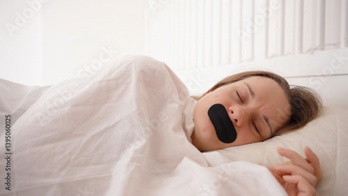 Woman Sleeping on Side Under White Blanket with Black Mouth Tape in Bright Bedroom, Silent Nighttime Nose Breathing Concept