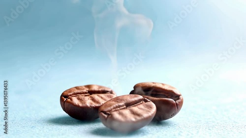 Steaming brown coffee beans, close-up, on a light blue textured surface.