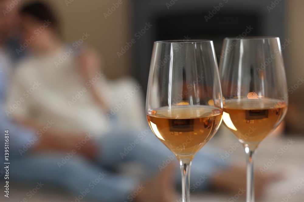Couple near fireplace at home, focus on glasses of wine