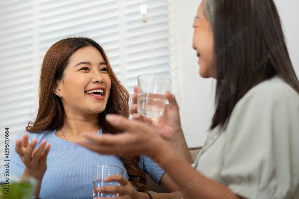 Socialization and Wellbeing. A mother and daughter sharing joyful moments while drinking water. Socialization and Wellbeing. A mother and daughter sharing joyful moments while drinking water.