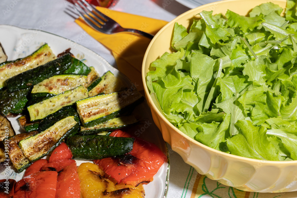dettagli di piatti riempiti con verdure varie, quali insalata, zucchine e peperoni a fette, su un tavolo apparecchiato