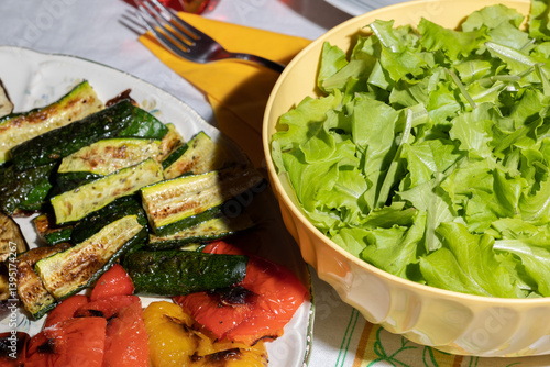 Obraz na płótnie dettagli di piatti riempiti con verdure varie, quali insalata, zucchine e peperoni a fette, su un tavolo apparecchiato w salonie