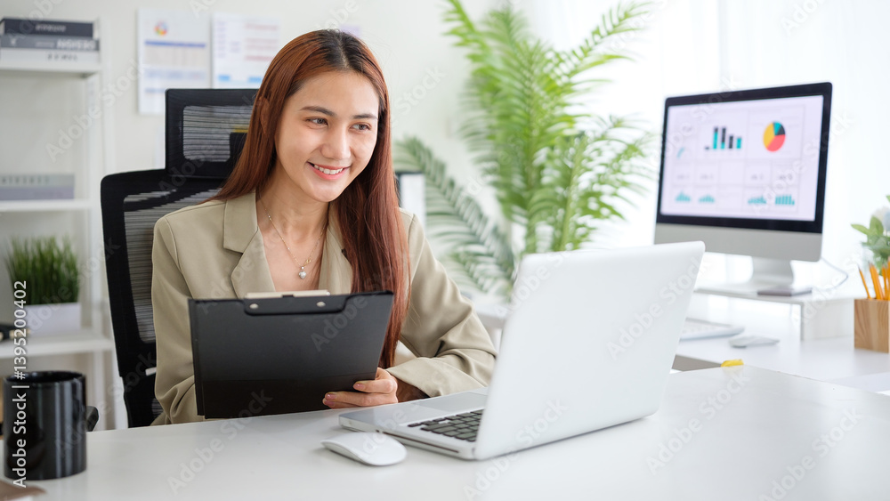 Smiling youn businesswoman working on a laptop in a bright, modern office. Smiling youn businesswoman working on a laptop in a bright, modern office.