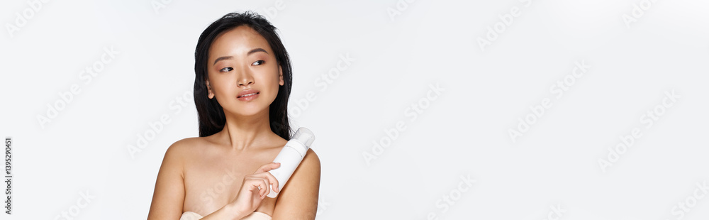 Young asian woman showcasing beauty products in a bright, minimalist studio environment