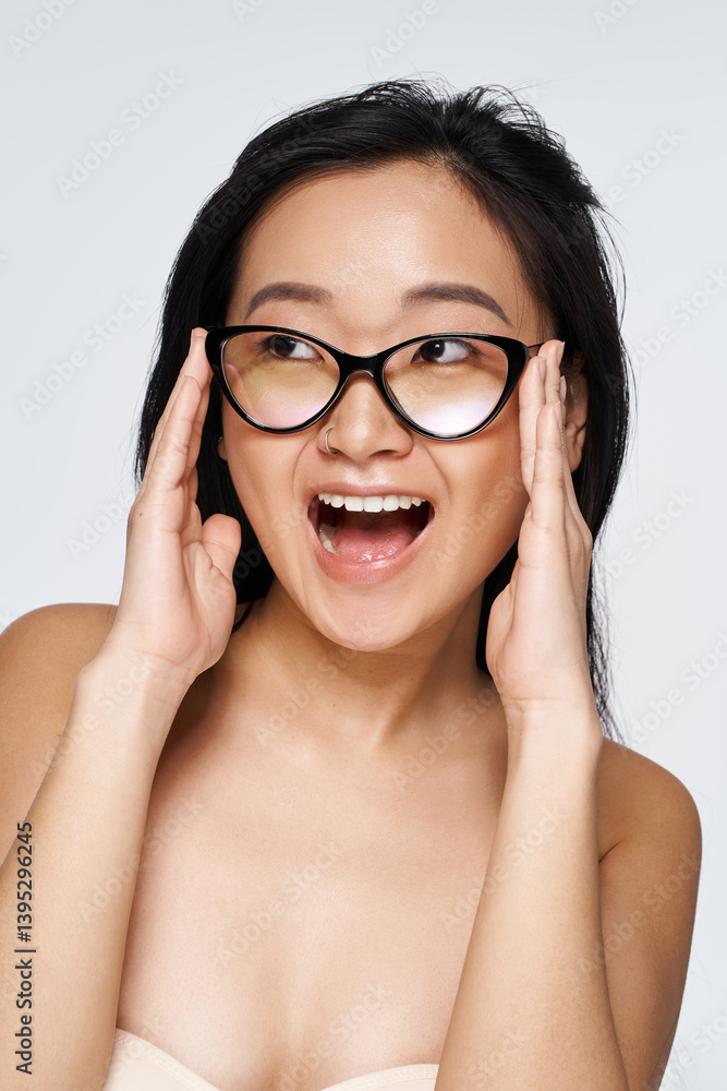 Young woman expresses joy with excited expression while wearing fashionable glasses Young woman expresses joy with excited expression while wearing fashionable glasses