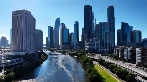 Enjoy a stunning view of Houston's skyline reflecting on the calm river. Lush greenery complements the modern architecture, creating a picturesque urban landscape under a blue sky