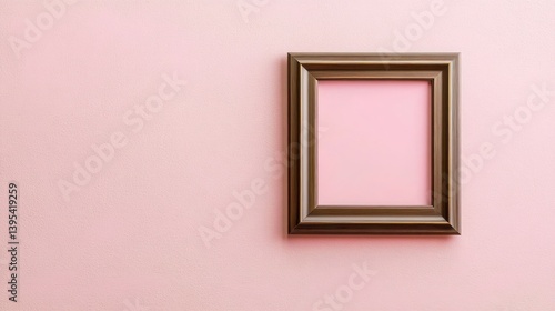 A small rectangular frame with a brushed bronze finish, off-center on a light pink wall, creating a chic vintage look.