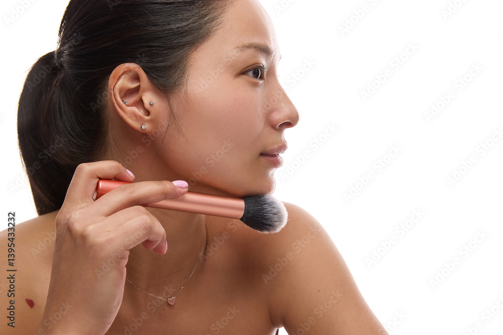 Side view portrait of young woman with clean, smooth skin and nude makeup holding makeup brush next to face on white background. Concept of skincare, natural beauty, wellness, makeup accessories Side view portrait of young woman with clean, smooth skin and nude makeup holding makeup brush next to face on white background. Concept of skincare, natural beauty, wellness, makeup accessories