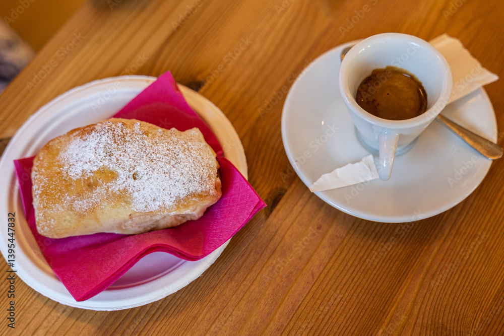 caffè espresso in tazza con dolce di pastafrolla ,con ripieno di marmellata, su un tavolo di legno, in un bar, di giorno