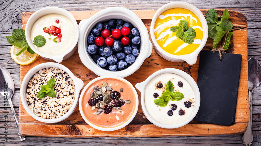 Selection of Fresh Yogurts with Berries and Herbs on Rustic Wooden Platter with Decorative Elements Selection of Fresh Yogurts with Berries and Herbs on Rustic Wooden Platter with Decorative Elements