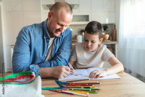 Caucasian boy doing homework with his dad. A handsome young man helping his son with school work at home. It's important to learn and get an education. A parent and child working on a project.