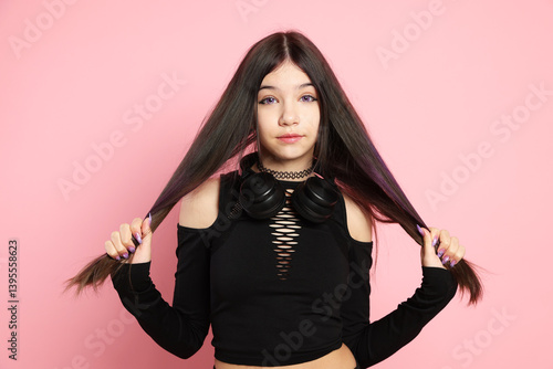 Teenage girl with headphones posing on pink background. Makeup and clothes in anime style