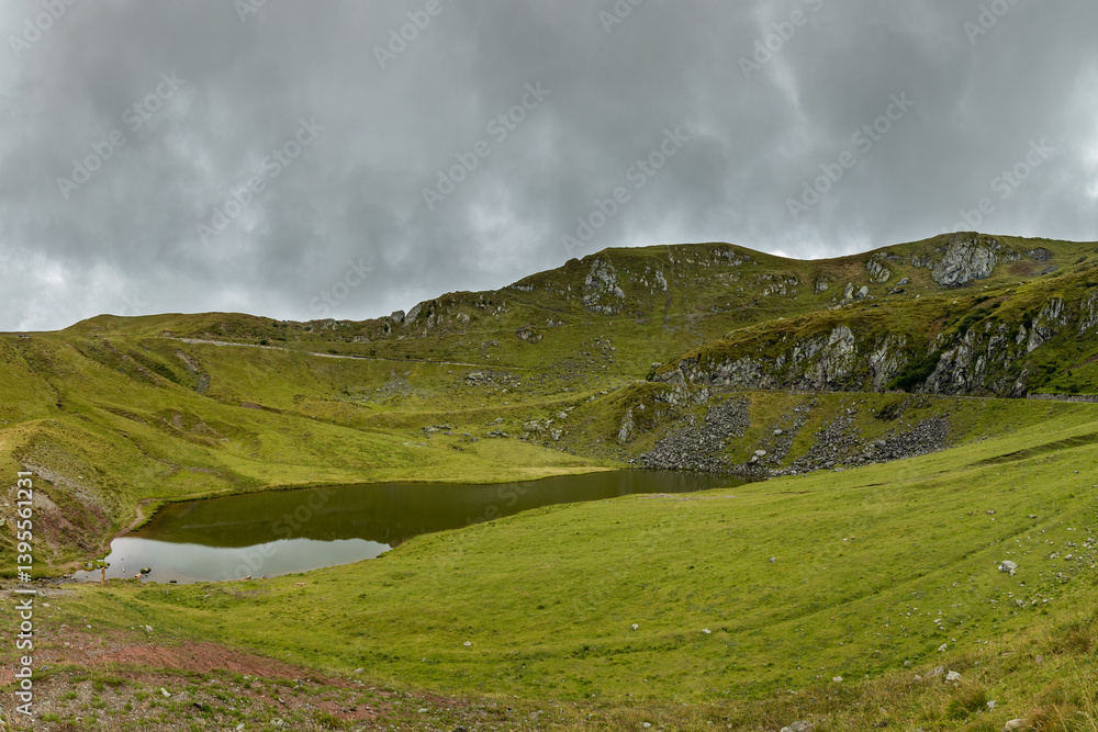panoramica sul Lago di Dimon nel suo ambiente naturale nel Friuli Venezia Giulia settentrionale, tra le cime delle montagne, circondato da verdi prati, di giorno, con cielo nuvoloso, in estate