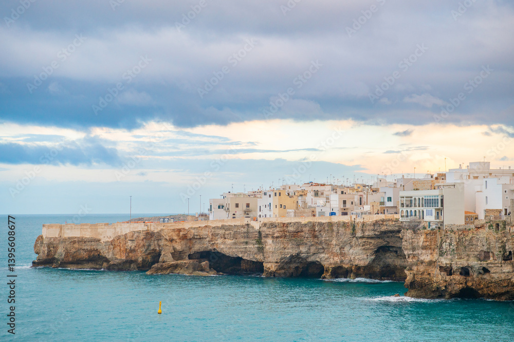View of houses on cliff in Polignano a Mare at sunset, Puglia, Italy. Travel photography. Golden hour landscape. View of houses on cliff in Polignano a Mare at sunset, Puglia, Italy. Travel photography. Golden hour landscape.