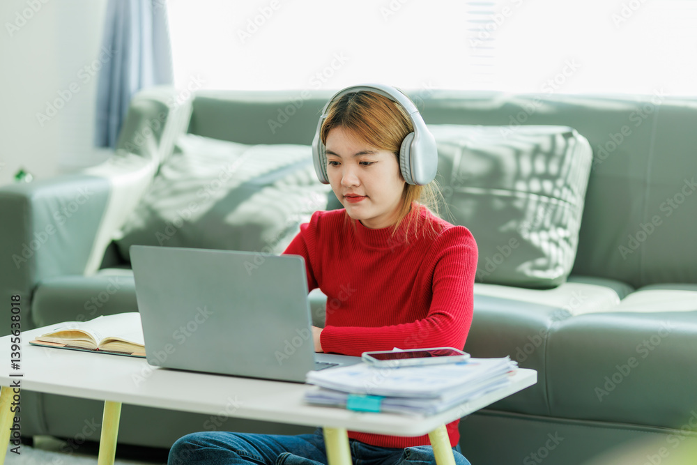 A young woman is studying online at home, taking notes and thoughtfully following along with the teacher's lecture. A young woman is studying online at home, taking notes and thoughtfully following along with the teacher's lecture.