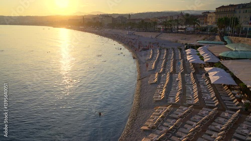 Wallpaper Mural Aerial view of multiple, empty loungers on the beach, with people swimming and relaxing at sunset in Nice, France Torontodigital.ca