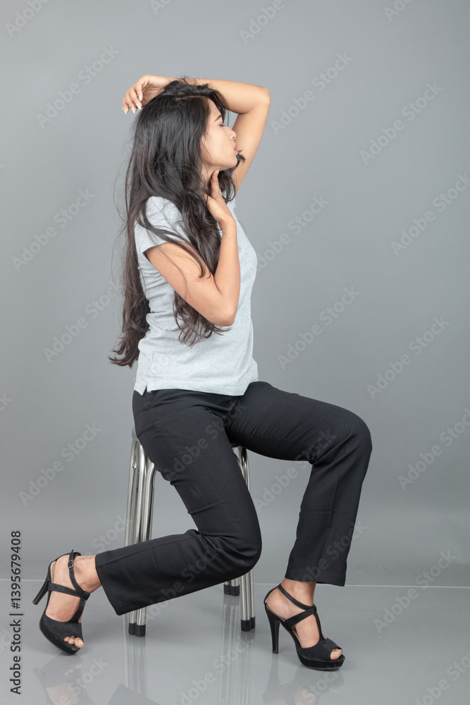 A confident woman dressed in casual business attire sits on a modern stool in a studio setup, evoking professionalism, elegance, and poise suitable for fashion or business-themed projects. A confident woman dressed in casual business attire sits on a modern stool in a studio setup, evoking professionalism, elegance, and poise suitable for fashion or business-themed projects.