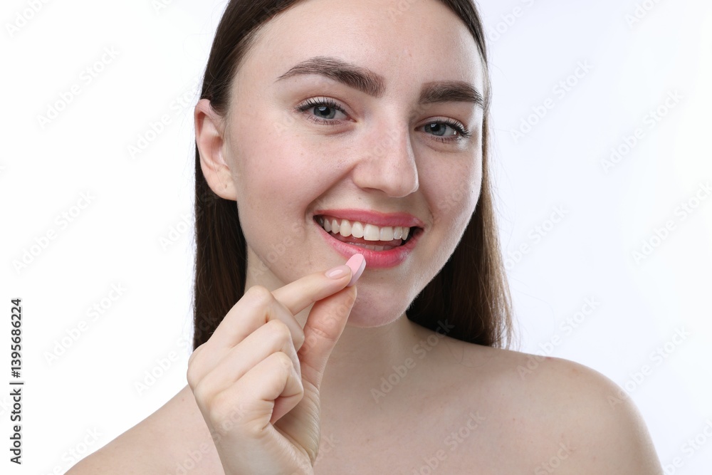 Smiling woman taking collagen pill on white background Smiling woman taking collagen pill on white background