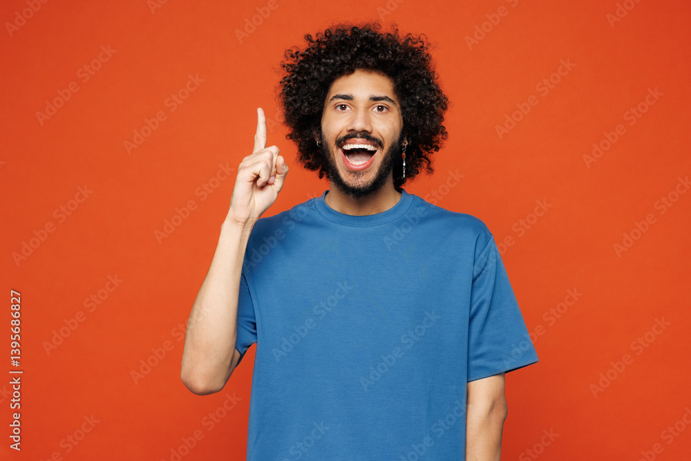 Young insighted proactive man of African American ethnicity he wears blue t-shirt casual clothes holding index finger up with great new idea isolated on plain red orange background. Lifestyle concept. Young insighted proactive man of African American ethnicity he wears blue t-shirt casual clothes holding index finger up with great new idea isolated on plain red orange background. Lifestyle concept.