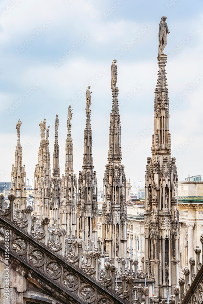 View of the gothic ornate spires and statues adorning the rooftop of the Milan Cathedral (Duomo di Milano) in Italy. View of the gothic ornate spires and statues adorning the rooftop of the Milan Cathedral (Duomo di Milano) in Italy.