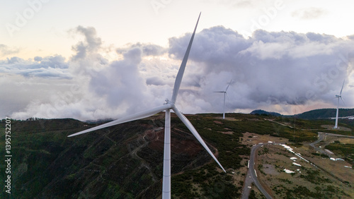 Captivating wind turbines gracefully spinning under a dramatic sky on a tranquil mountain landscape during sunset