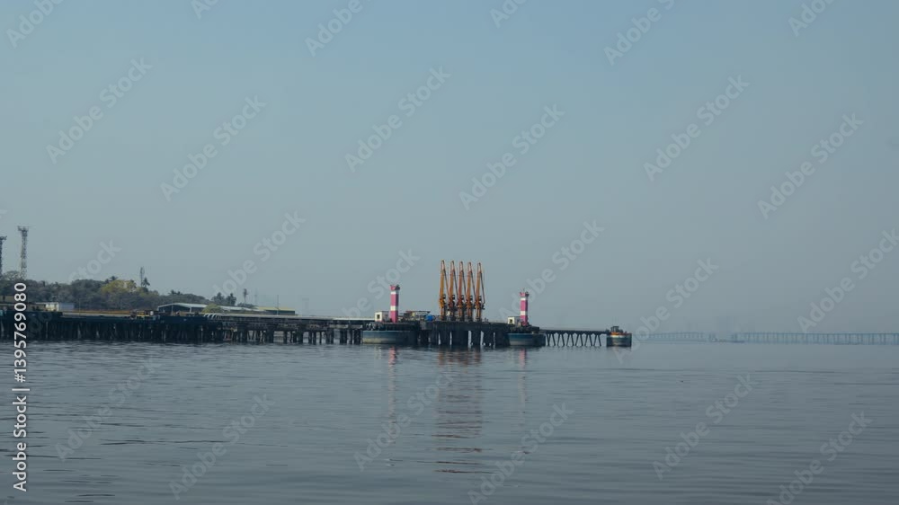 A colorful jetty and an oil ship dock at the sea, creating a vibrant scene. The small port behind adds to the coastal charm. A colorful jetty and an oil ship dock at the sea, creating a vibrant scene. The small port behind adds to the coastal charm.