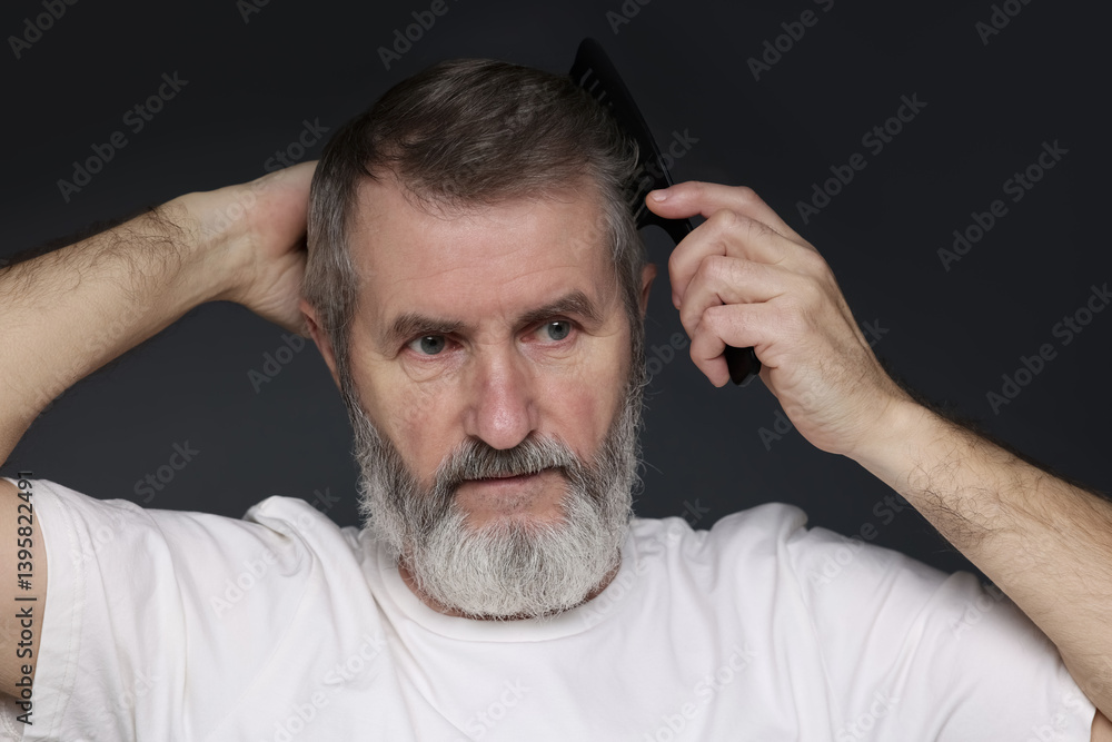 Obraz premium Handsome man combing his hair on dark grey background