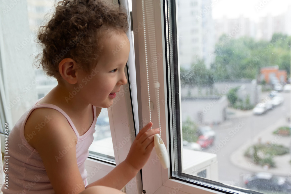 Curly child looks out the window sitting on the windowsill Curly child looks out the window sitting on the windowsill