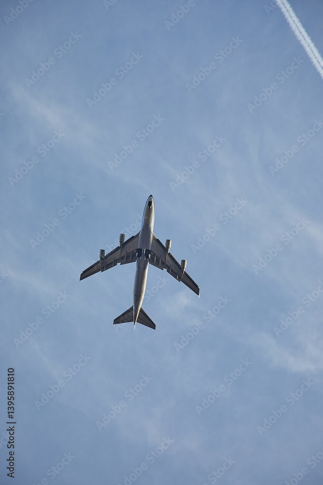 Large jet airplane flying overhead, blue sky