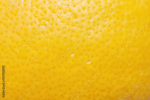 Lemon with water drops macro photo as background. Lemon skin is yellow, thin focus part.
