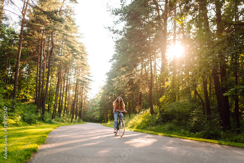 Wallpaper Mural Young woman enjoying bike ride in sunny forest. Beautiful tourist having fun at sunset. Concept of rest, walks. Active lifestyle. Torontodigital.ca