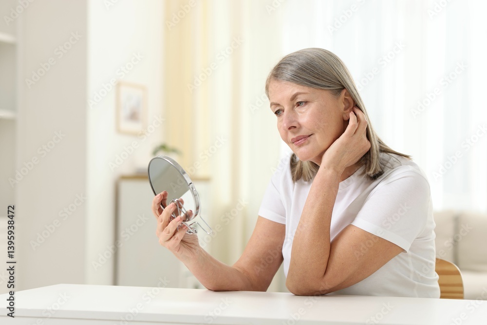 Woman with healthy skin looking at mirror at table indoors Woman with healthy skin looking at mirror at table indoors