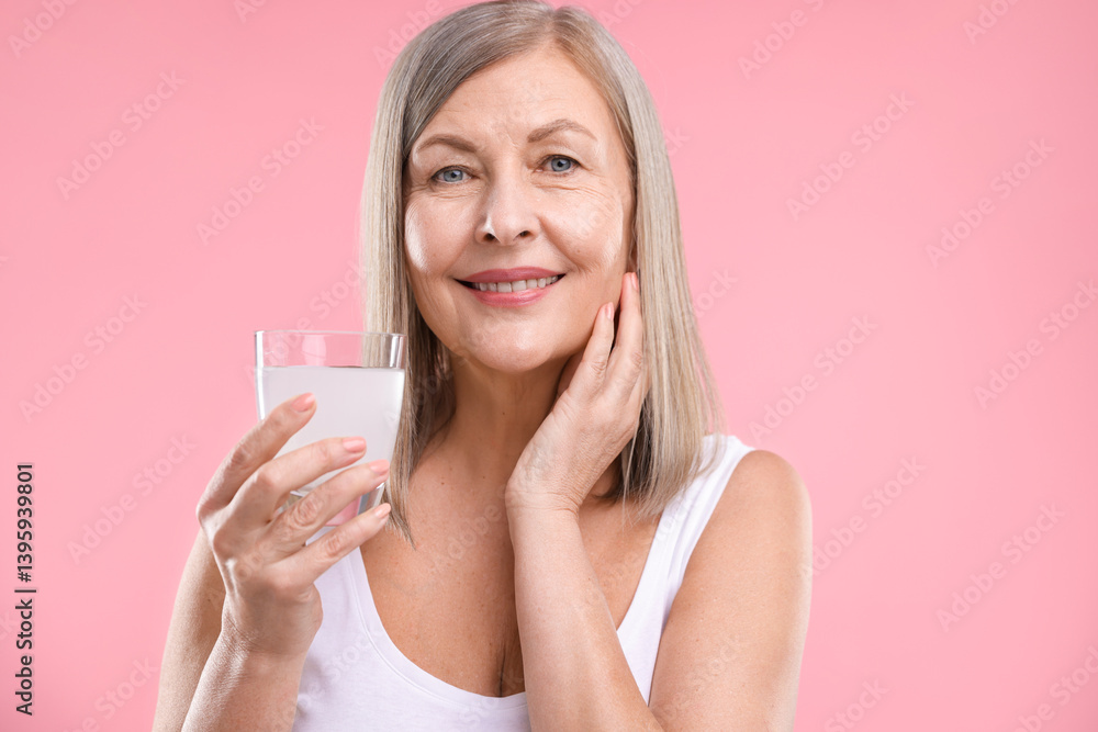 Smiling woman with glass of collagen water on pink background Smiling woman with glass of collagen water on pink background