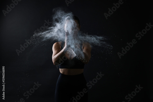 Obraz na płótnie Woman clapping hands with talcum powder before training on black background w salonie