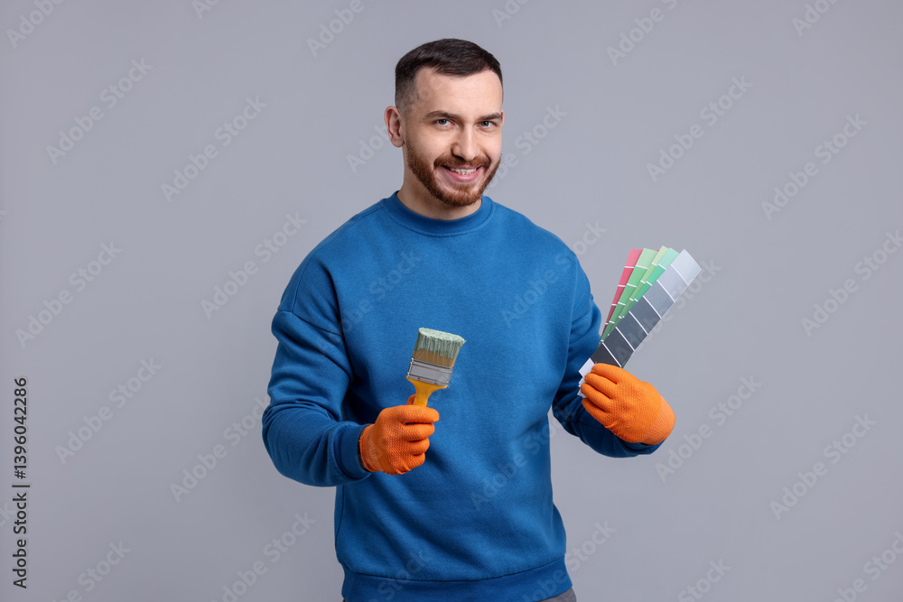 Man with paintbrush and color selection chart on light grey background Man with paintbrush and color selection chart on light grey background