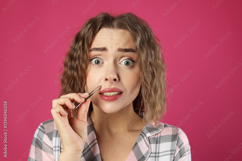 Emotional woman plucking her mustache with tweezers on pink background Emotional woman plucking her mustache with tweezers on pink background