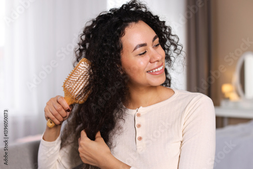 Schilderij op canvas Smiling young woman brushing her curly hair at home