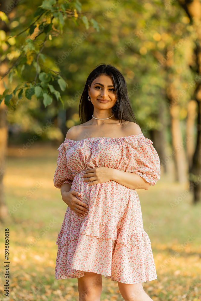 Beautiful brunette pregnant woman walks in the park at sunset in summer Beautiful brunette pregnant woman walks in the park at sunset in summer