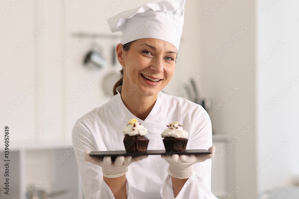 Happy confectioner with delicious cupcakes in kitchen Happy confectioner with delicious cupcakes in kitchen