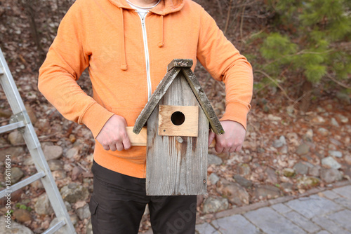 Photography Man's hands holding an old wooden bird house for a tit birds after repairing and
