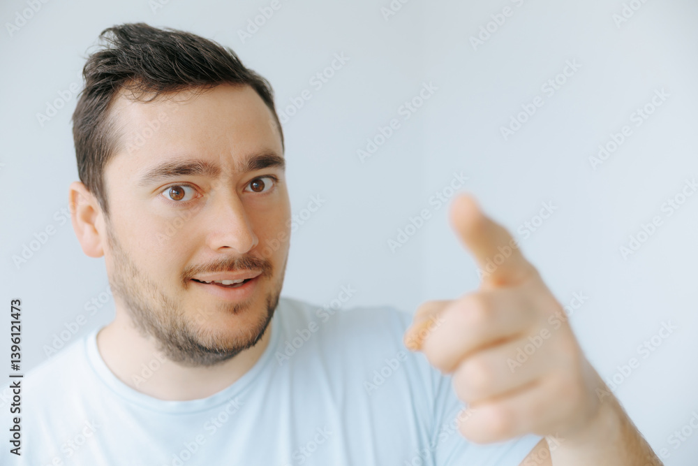 Man with short hair points directly while smiling at the camera indoors Man with short hair points directly while smiling at the camera indoors