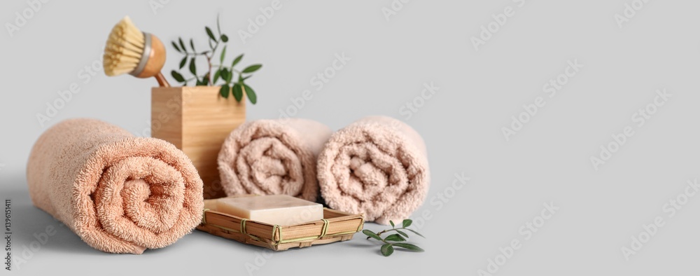 Rolled towels, green twigs, brush and soap bar on grey background with space for text Rolled towels, green twigs, brush and soap bar on grey background with space for text
