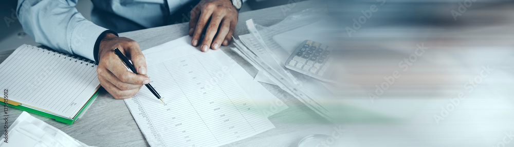Business Person Calculating Invoices Using Calculator In Office Business Person Calculating Invoices Using Calculator In Office