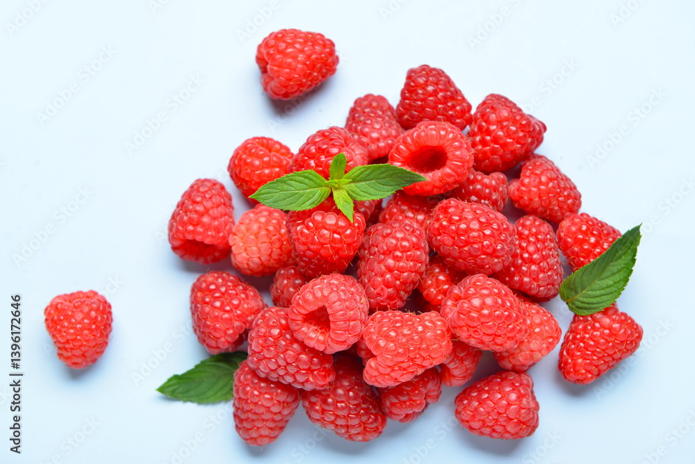 Heap of fresh raspberries and mint on blue background Heap of fresh raspberries and mint on blue background