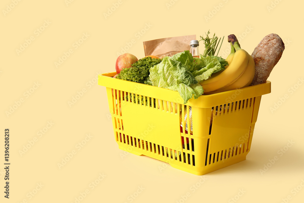 Yellow shopping basket full of different fresh products and apples on beige background
