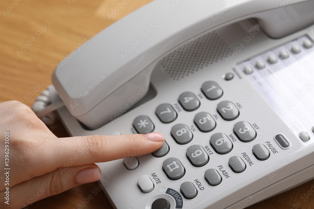 Woman dialing number on telephone at wooden table, closeup Woman dialing number on telephone at wooden table, closeup