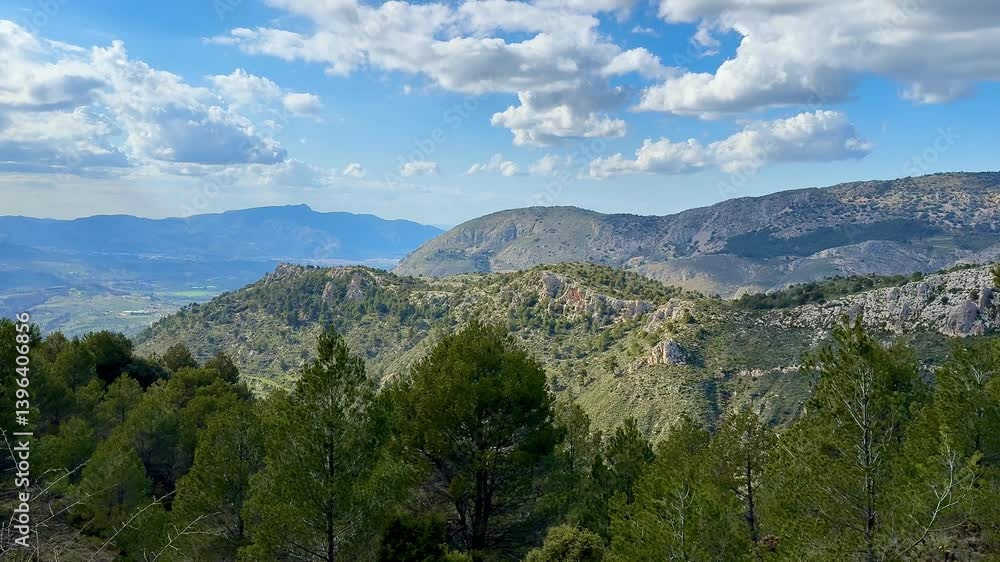 A stunning panoramic view of majestic mountains, lush greenery, and fluffy clouds under a clear blue sky A stunning panoramic view of majestic mountains, lush greenery, and fluffy clouds under a clear blue sky