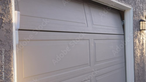 A closeup view of a partially elevated garage door, showcasing its unique design and surrounding elements in a typical residential area, highlighting architecture and landscaping